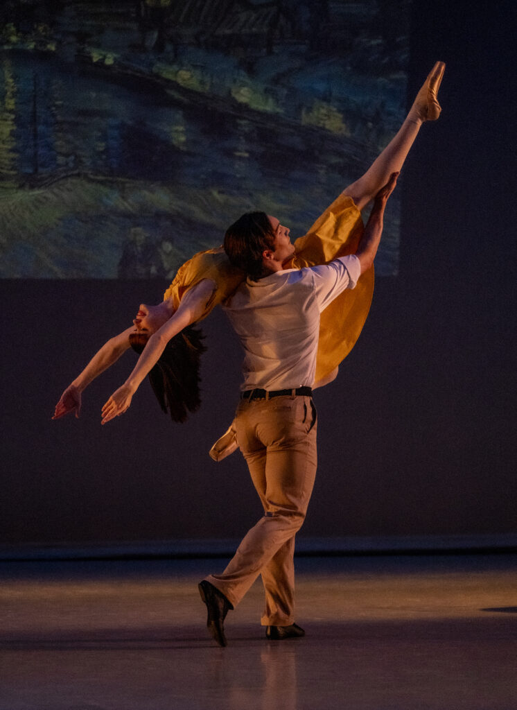 Male dancer lifts ballerina across the stage.