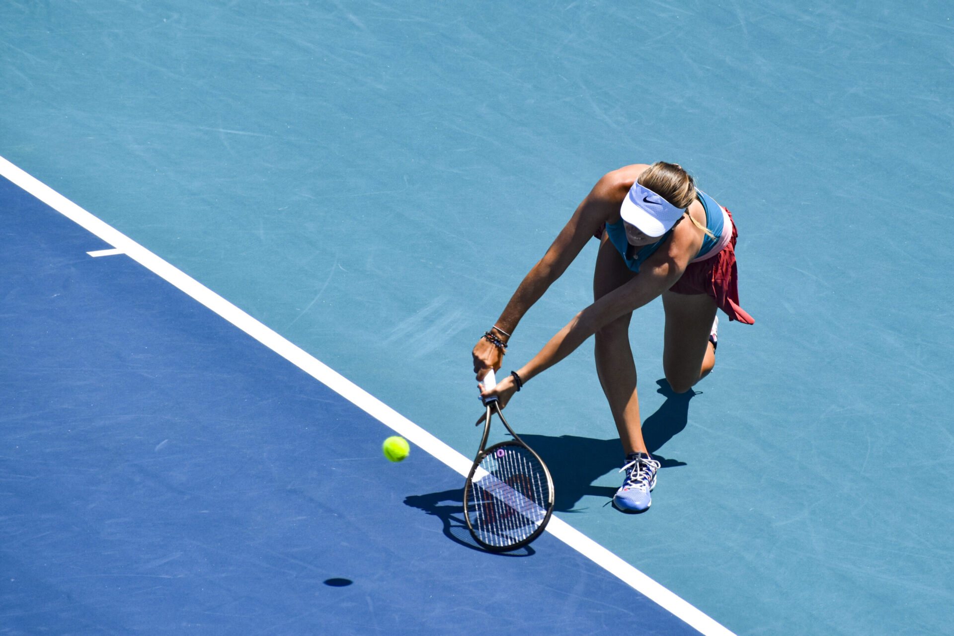 Tennis player scoops a ball at the baseline